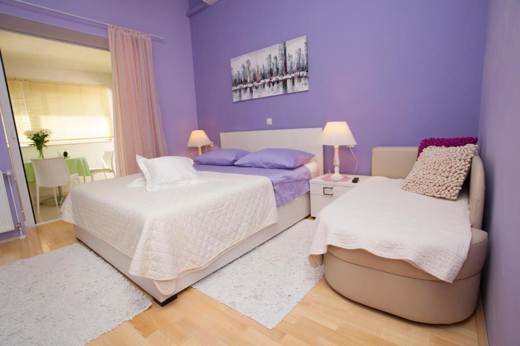 a purple bedroom with two beds and a chair at Villa Palma Apartments in Makarska
