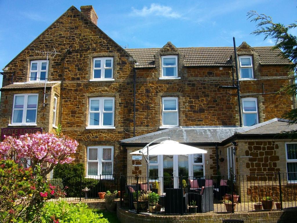 une maison en briques avec un parasol blanc devant elle dans l'établissement Gate Lodge Guest House, à Hunstanton