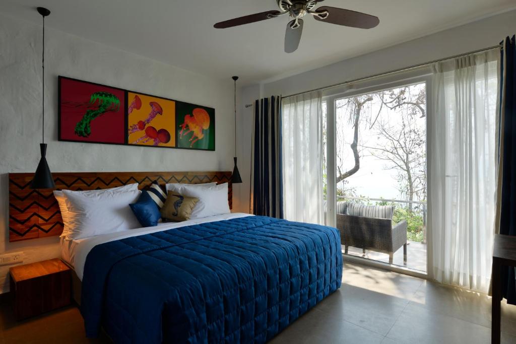 a bedroom with a blue bed and a sliding glass door at Cintacor Island Resort in Kārwār