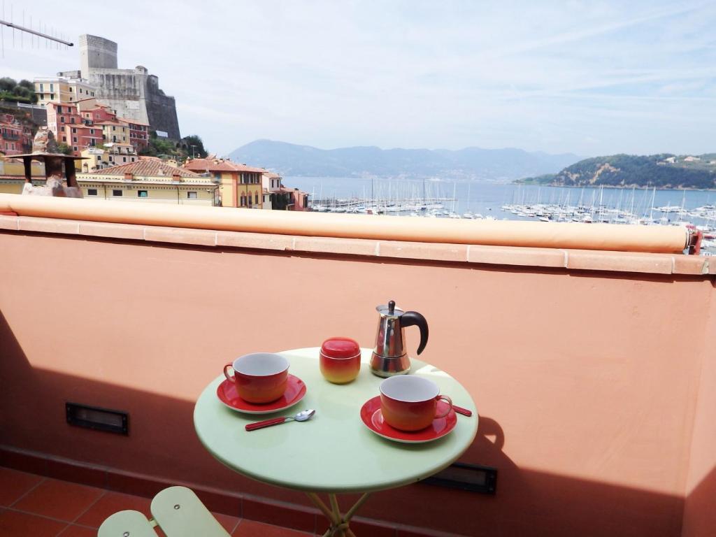 a table with two cups and a tea kettle on a balcony at Mansarda Laura in Lerici
