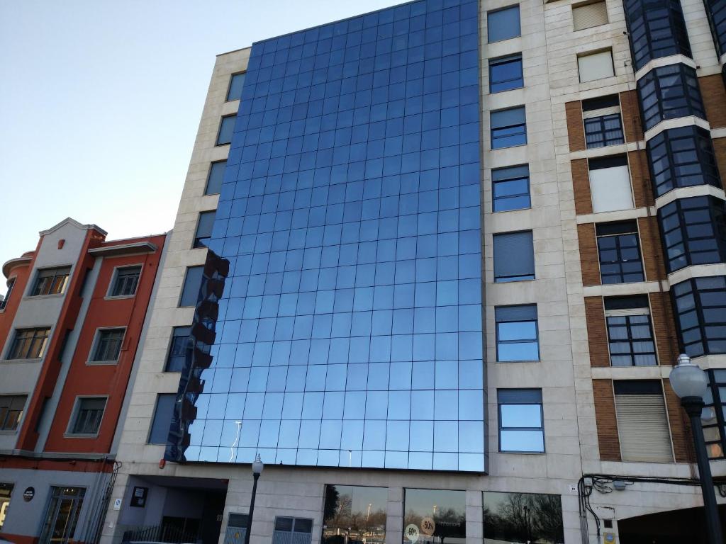 un edificio de oficinas con una fachada de espejo en Iradri, Apartamento Playa Gijón, en Gijón