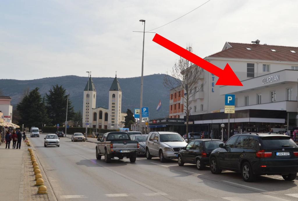 a red arrow on a city street with cars at Rooms Guardian in Međugorje