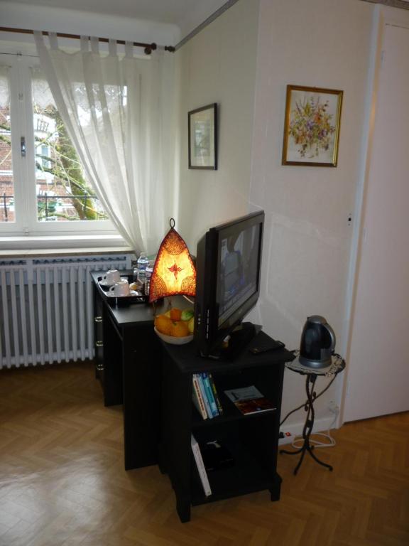 a living room with a television and a table with a lamp at au vieux cèdre in Mouvaux