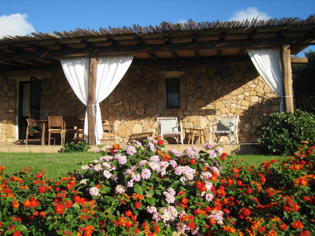 un jardín con flores y una casa de piedra en Le Tre Pietre, en Baja Sardinia