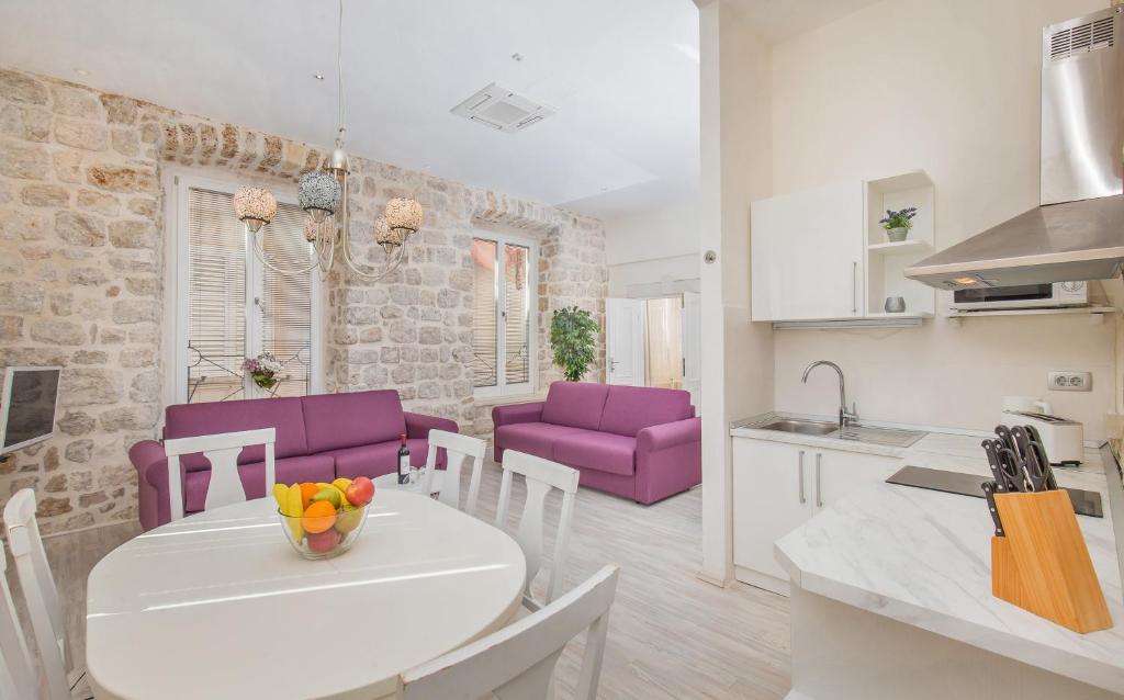 a kitchen and living room with a table and purple chairs at Lausion Apartments in Dubrovnik