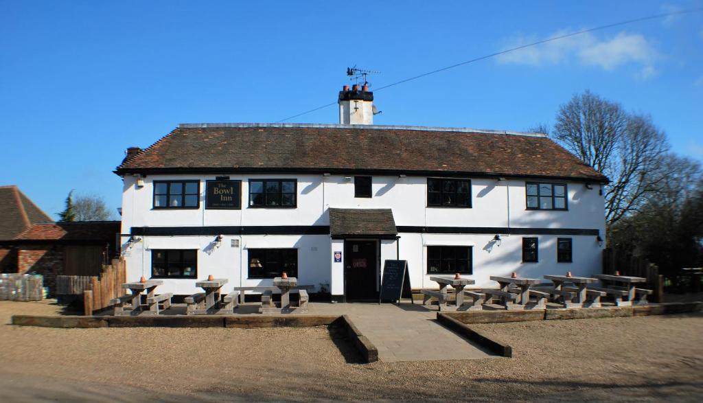 ein weißes Gebäude mit Tischen und Bänken davor in der Unterkunft The Bowl Inn in Charing