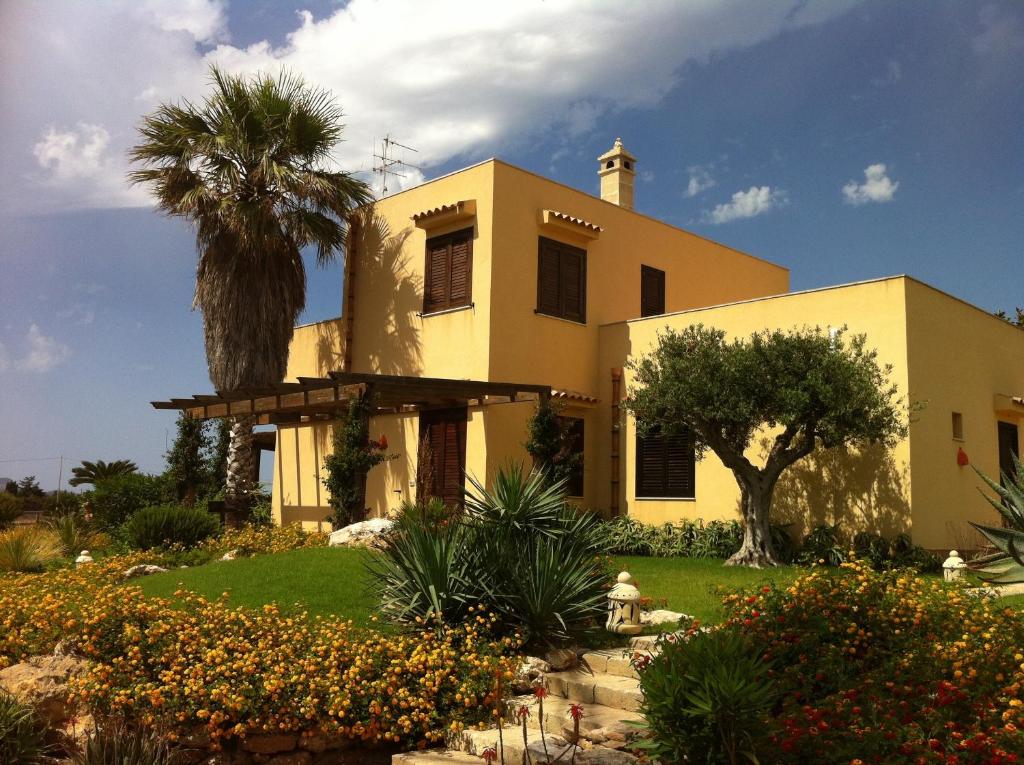 una casa amarilla con una palmera delante de ella en Il Giardino delle Aloe en Favignana