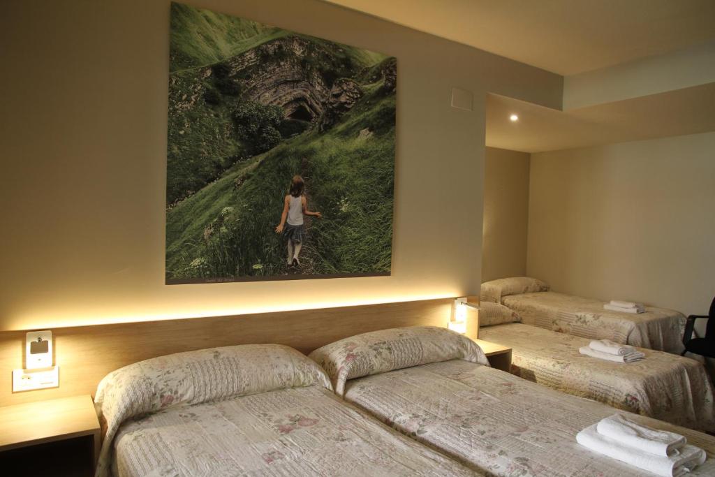 una camera d'albergo con due letti e un dipinto sul muro di Pensión Acella a Pamplona