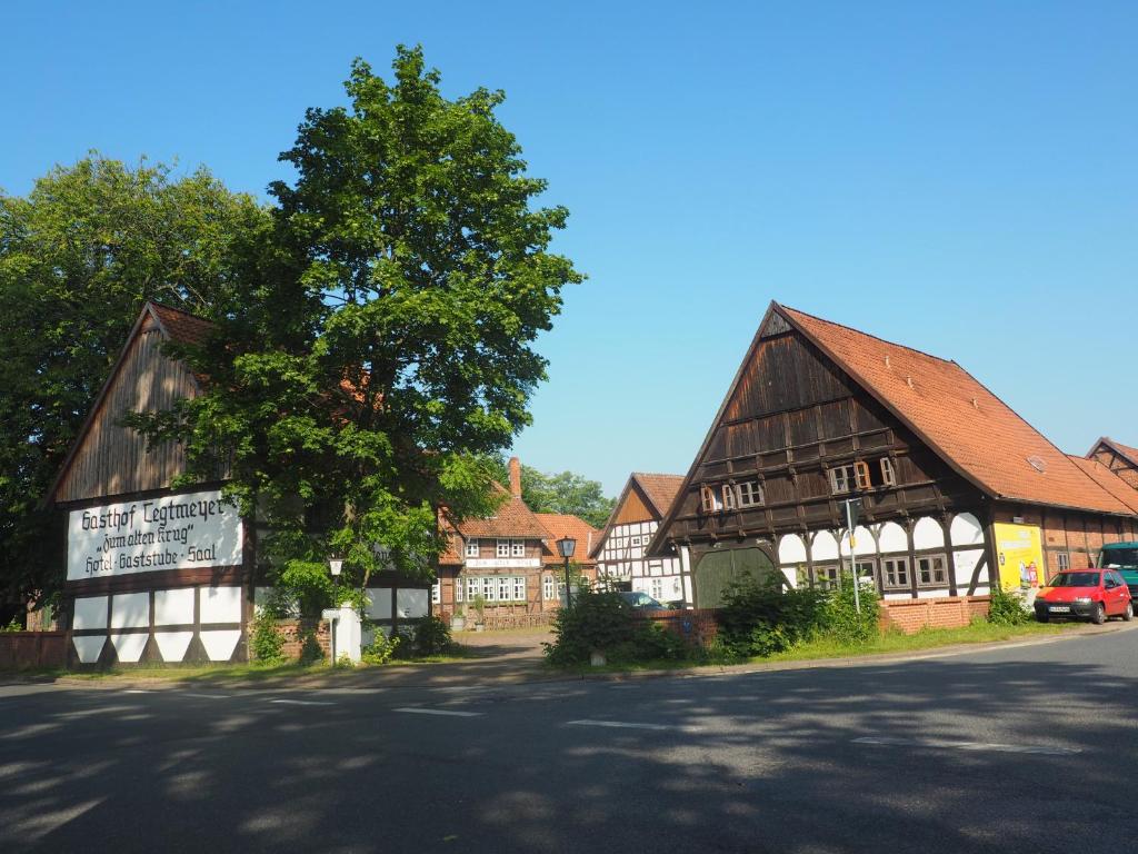 un grand bâtiment en bois avec un arbre à côté d'une rue dans l'établissement Tegtmeyer zum alten Krug, à Langenhagen