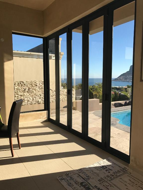 a room with sliding glass doors with a view of the ocean at Sunsetviews Hout Bay in Hout Bay