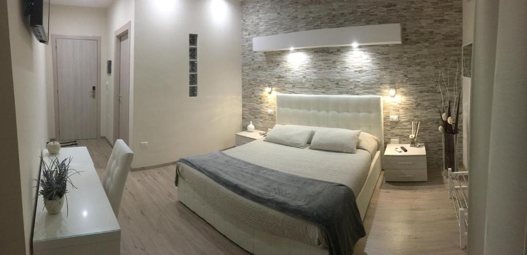 1 dormitorio con cama blanca y pared de ladrillo en Il Principe en Ravanusa