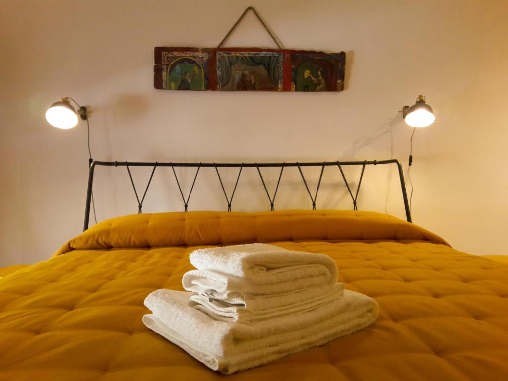 una pila de toallas en una cama con dos luces en L'altro capo del filo, en Siracusa