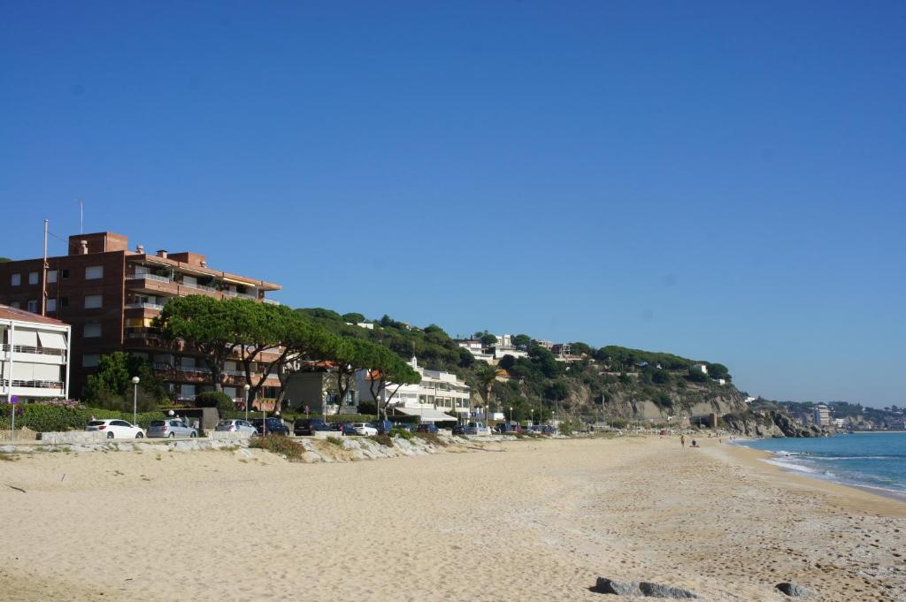 uma praia de areia com edifícios e o oceano em Musclera em Arenys de Mar