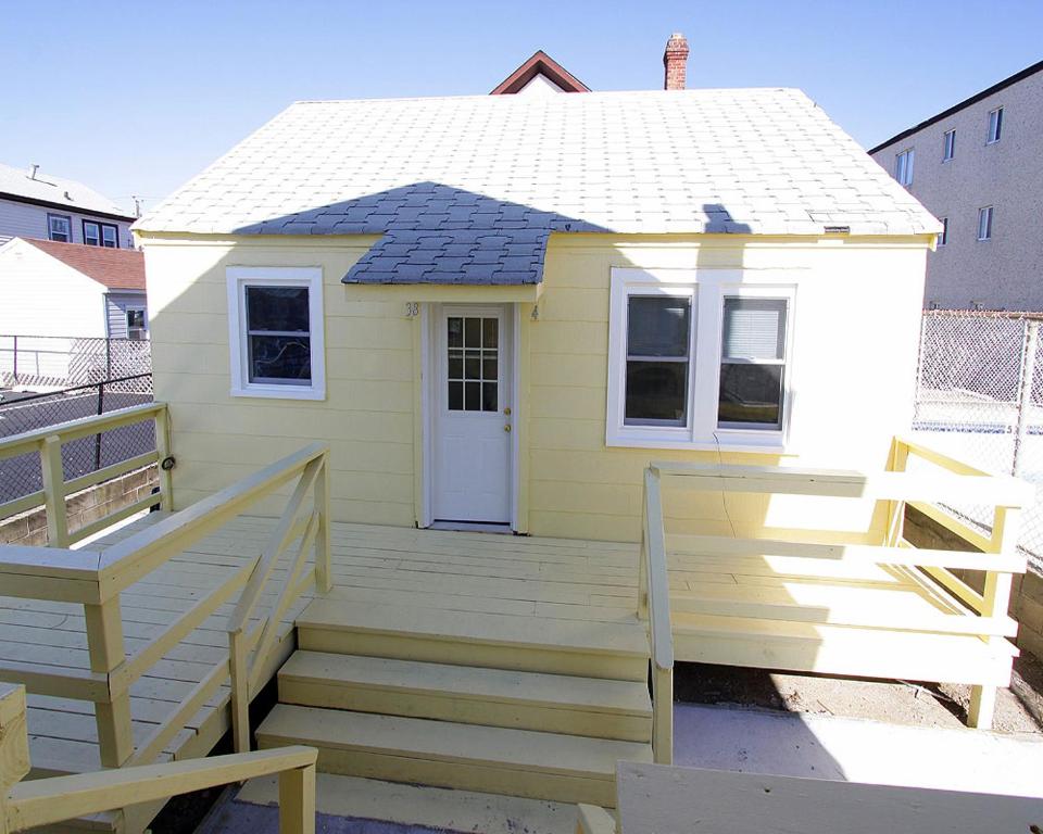 una pequeña casa amarilla con porche y escaleras en Shore Beach Houses - 38 D Lincoln Avenue, en Seaside Heights