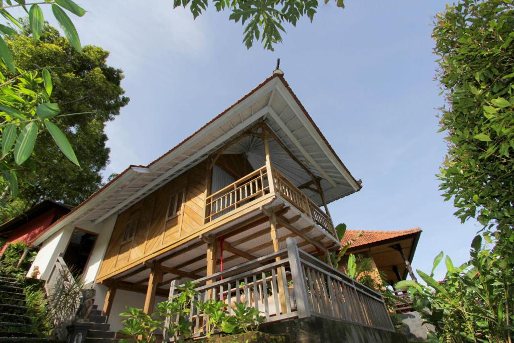 a house with a balcony on the side of it at Melanting Cottages in Munduk