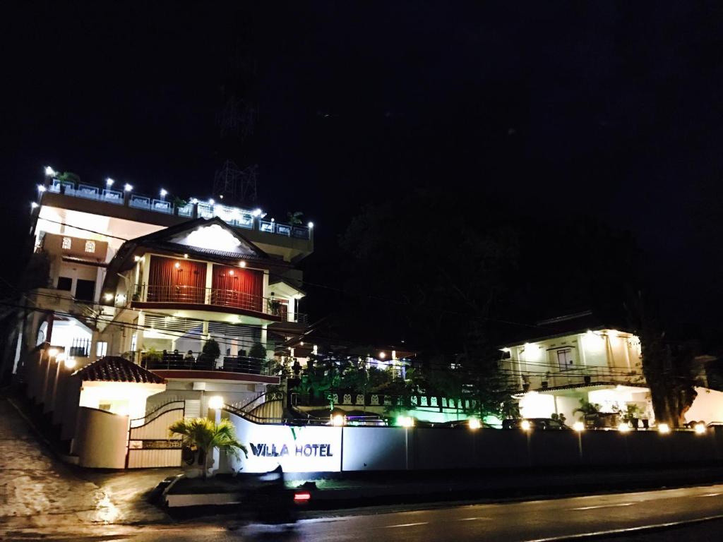 duży budynek z oświetleniem w nocy w obiekcie Villa Hotel w mieście Trikunamalaja
