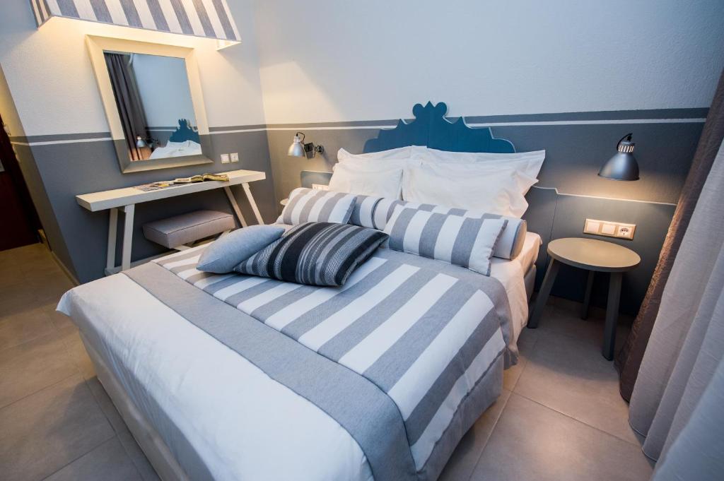 1 dormitorio con 1 cama con rayas azules y blancas en Alkyon Hotel, en Patitiri