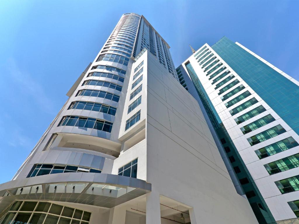 un edificio blanco alto con un cielo azul en el fondo en Currency Serviced Suites en Manila