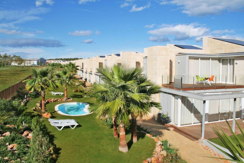 an aerial view of a house with a swimming pool and palm trees at L' Escala Resort in L'Escala