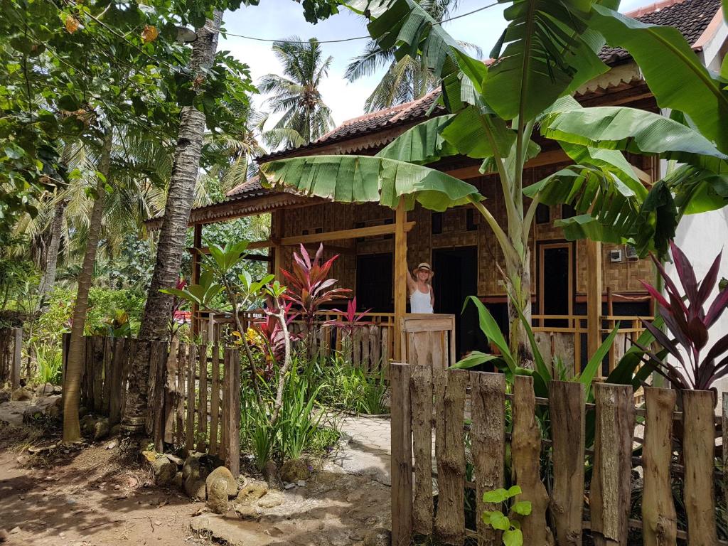 a woman standing in the doorway of a house at Red Island Bungalows in Pasanggaran