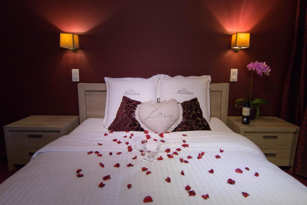 een bed met rozen erop en een hartvormig kussen bij Hotel Maraboe in Brugge