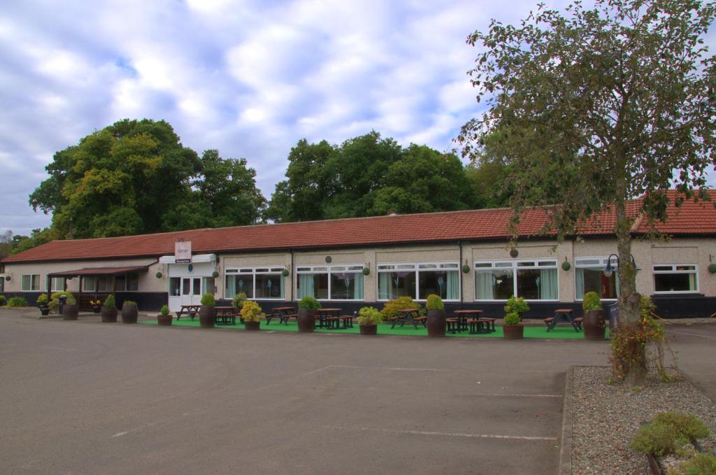 un edificio con muchas ventanas y bancos en Rob Roy Hotel, en Aberfoyle