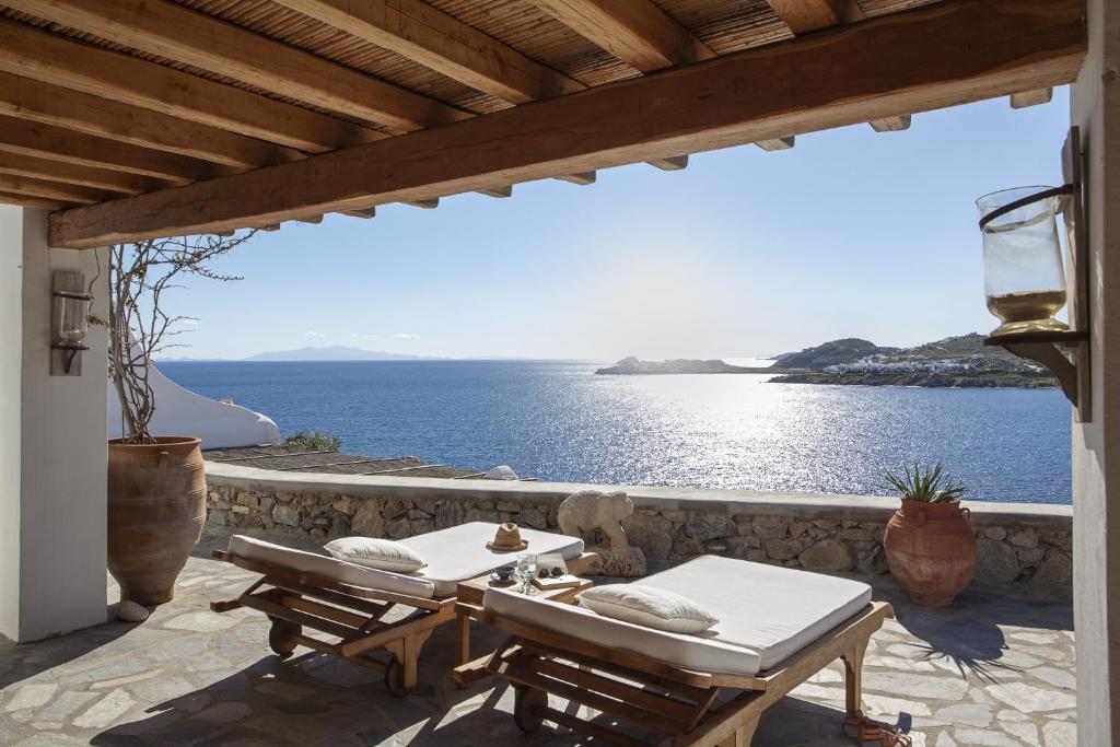 a patio with two tables and a view of the ocean at Beachfront Mykonos Guest House in Ornos