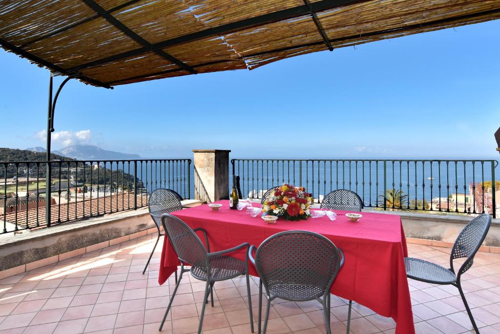 un tavolo con una tovaglia rossa e sedie su un balcone di La Ciucciara Holiday Homes a Massa Lubrense