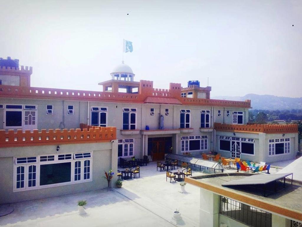 a large building with a patio with tables and chairs at Stargaze Hotel & Apartment in Abbottabad