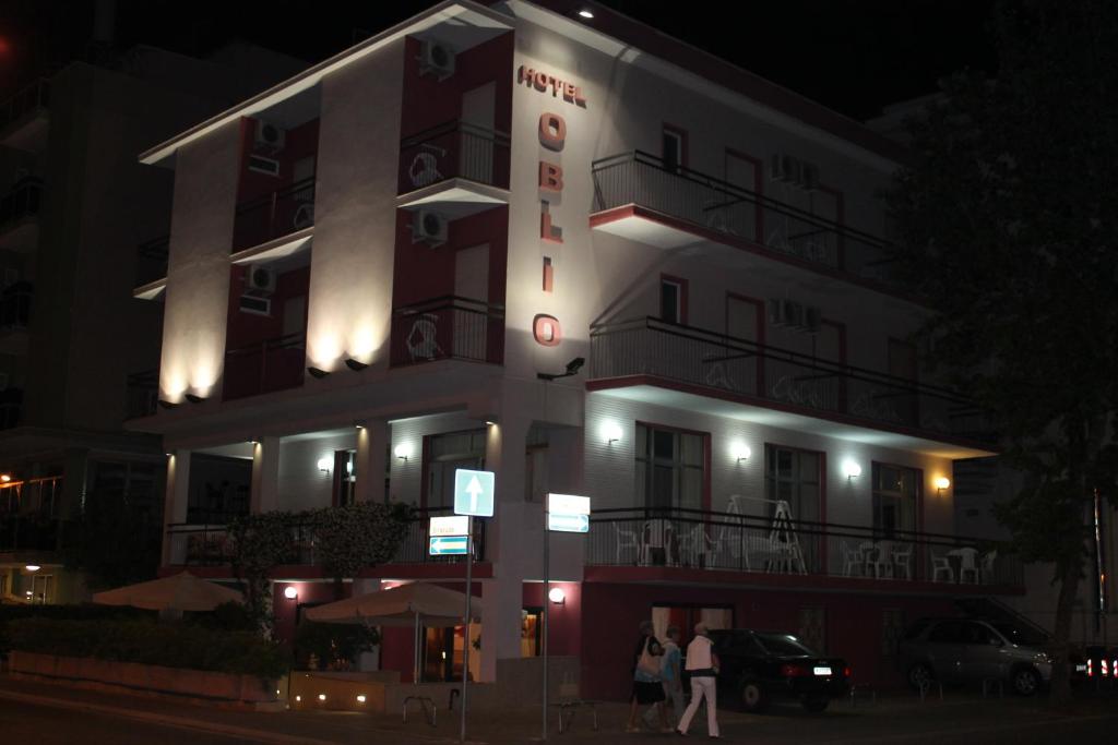 Un bâtiment avec des personnes debout à l'extérieur le soir dans l'établissement Hotel Oblio, à Rimini