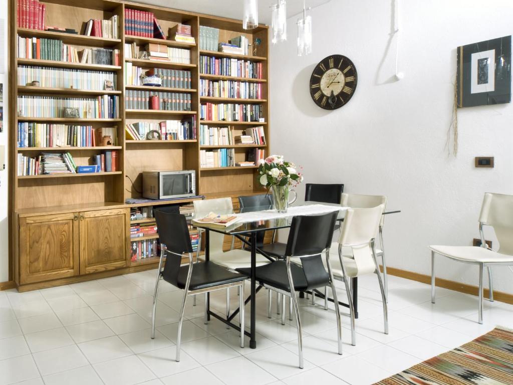 uma sala de jantar com mesa, cadeiras e estantes em Domo Silvia E Paolo em Nuoro