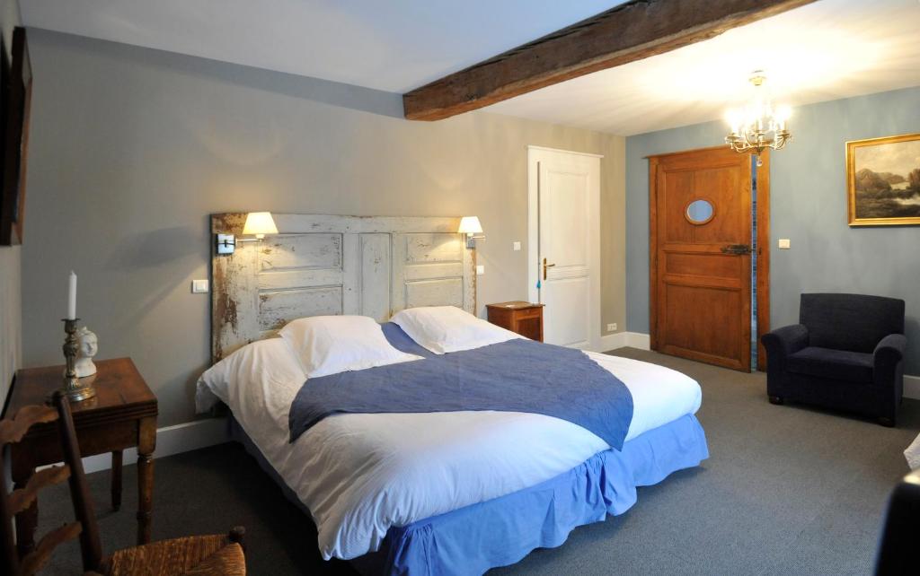 a bedroom with a large bed and a chair at Les Chambres d'hôtes Benoit Breton in Bulgnéville