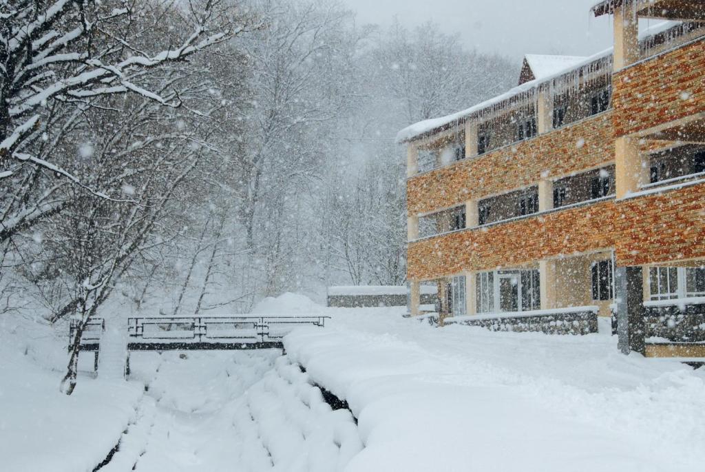 un parque cubierto de nieve con un edificio y un banco en Tsaghkahovit Hotel, en Tsaghkadzor