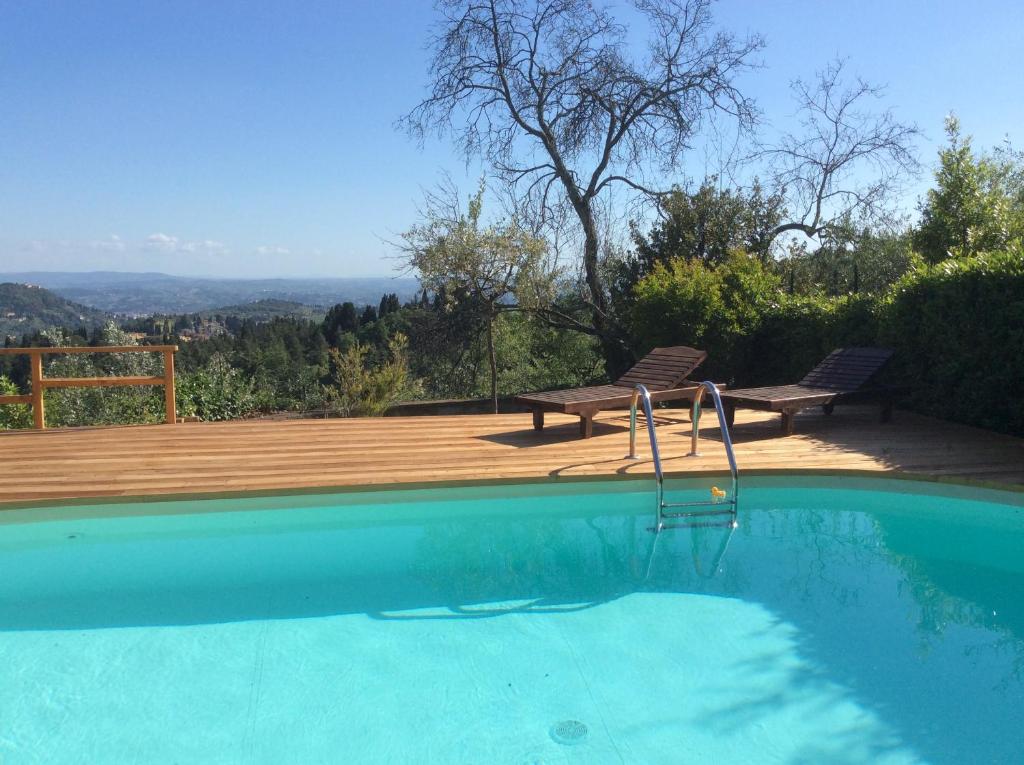 a swimming pool with two chairs and a wooden deck at Bed Breakfast La Paggeria in Trespiano