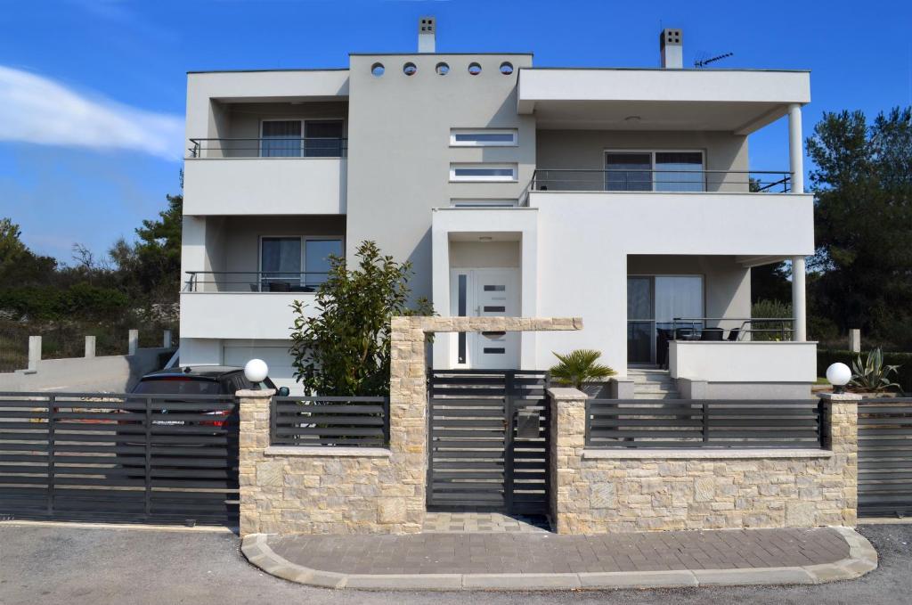 a white house with a fence in front of it at Apartments Miočić in Zadar