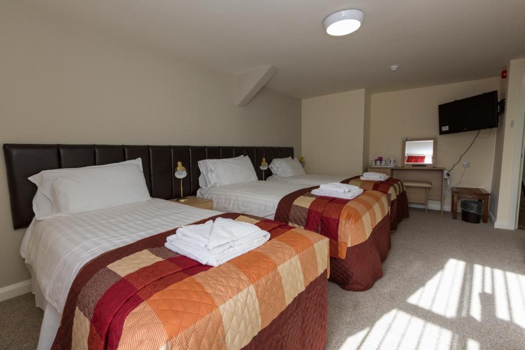a hotel room with two beds and a television at The Golf Hotel in Silloth