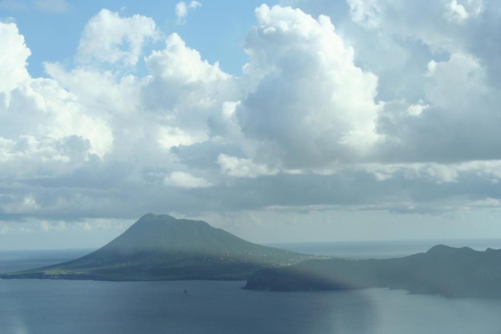 a mountain in the ocean under a cloudy sky at Statia Lodge in Oranjestad