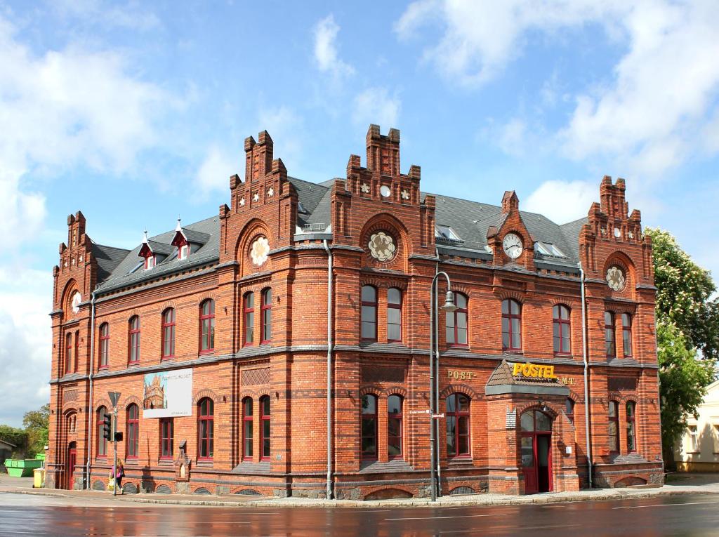 duży ceglany budynek z dwoma zegarami na nim w obiekcie Postel Wolgast w mieście Wolgast