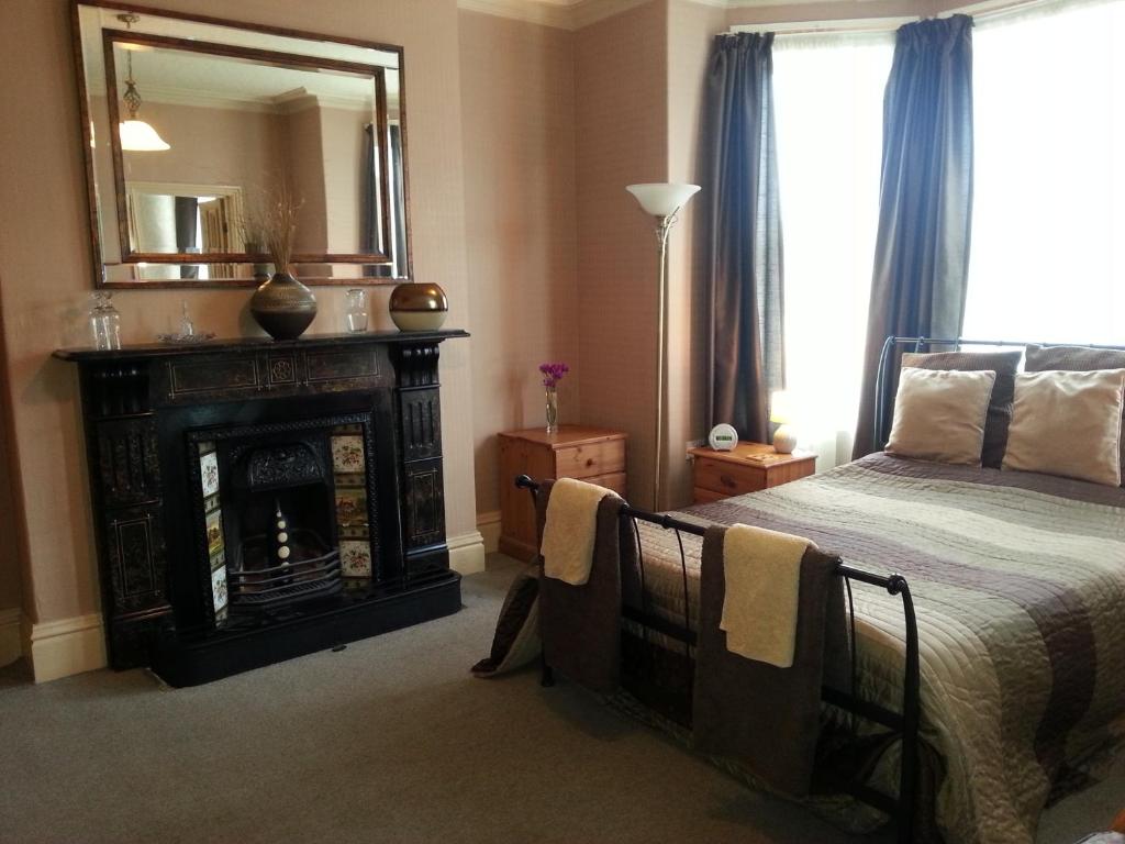 a bedroom with a bed with a fireplace and a mirror at Riftswood in Whitby