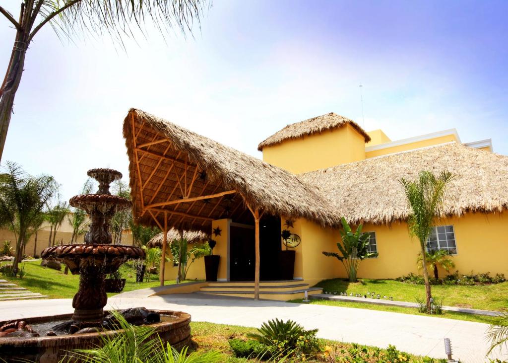 une maison avec un toit de chaume et une fontaine dans l'établissement Zar Colima, à Colima