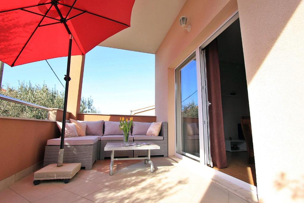 a patio with a couch and a red umbrella at Priska Apartment in Kaštela
