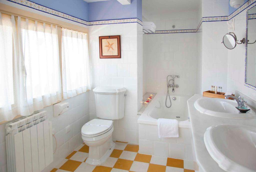 y baño con aseo, bañera y lavamanos. en Casona de La Paca, en Cudillero