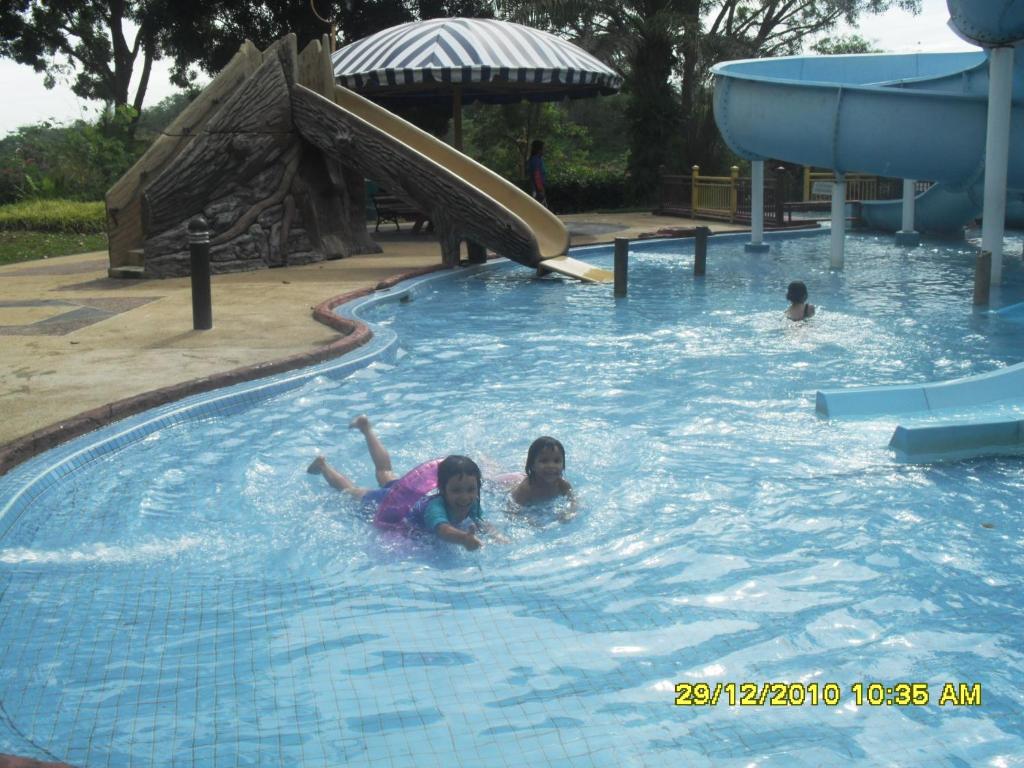 - deux enfants nagent dans une piscine dans l'établissement Famosa D Savoy 3-Bedroom Condo in Alor Gajah, à Malacca