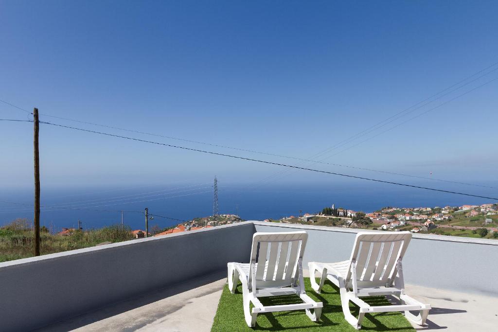 two chairs sitting on a balcony with a view of the ocean at Casa do Serrado in Ponta do Sol