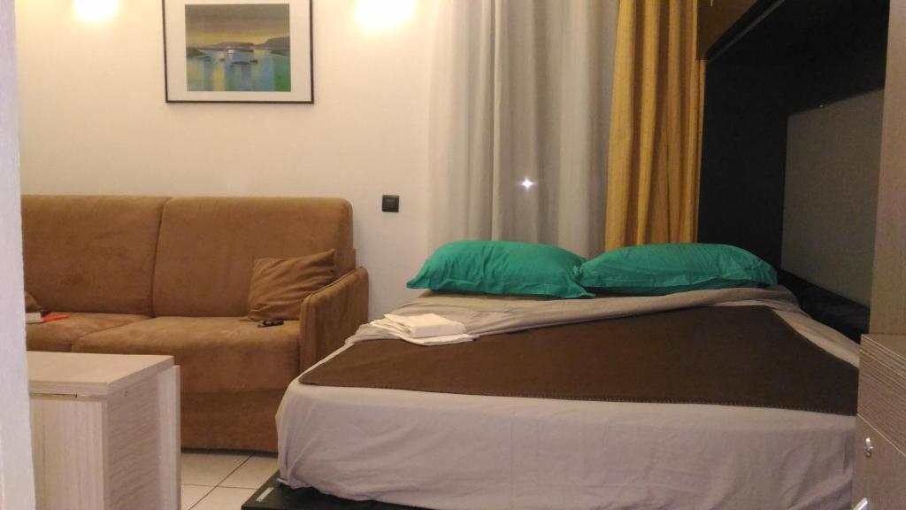 ein Bett mit zwei grünen Kissen und einer Couch in der Unterkunft Californie Appartement in Nizza