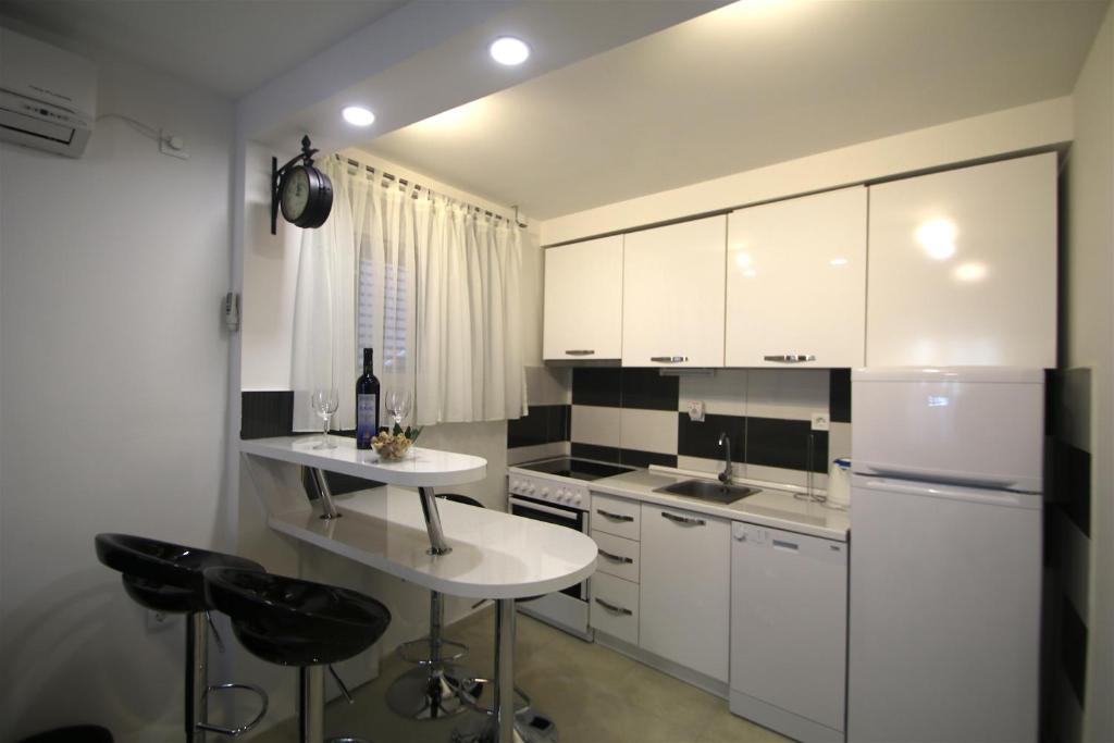 kuchnia z białymi szafkami i urządzeniami w kolorze czarno-białym w obiekcie Apartment Adriatic Gem w Splicie