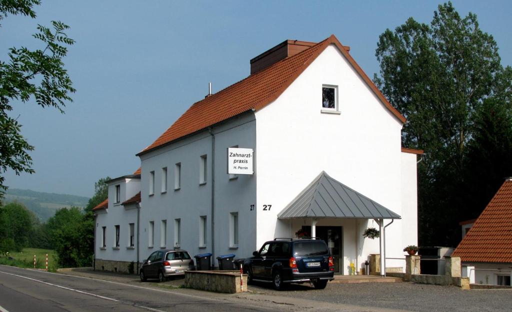 ein weißes Gebäude mit davor geparkt in der Unterkunft Gästehaus Perrin in Bliesmengen-Bolchen