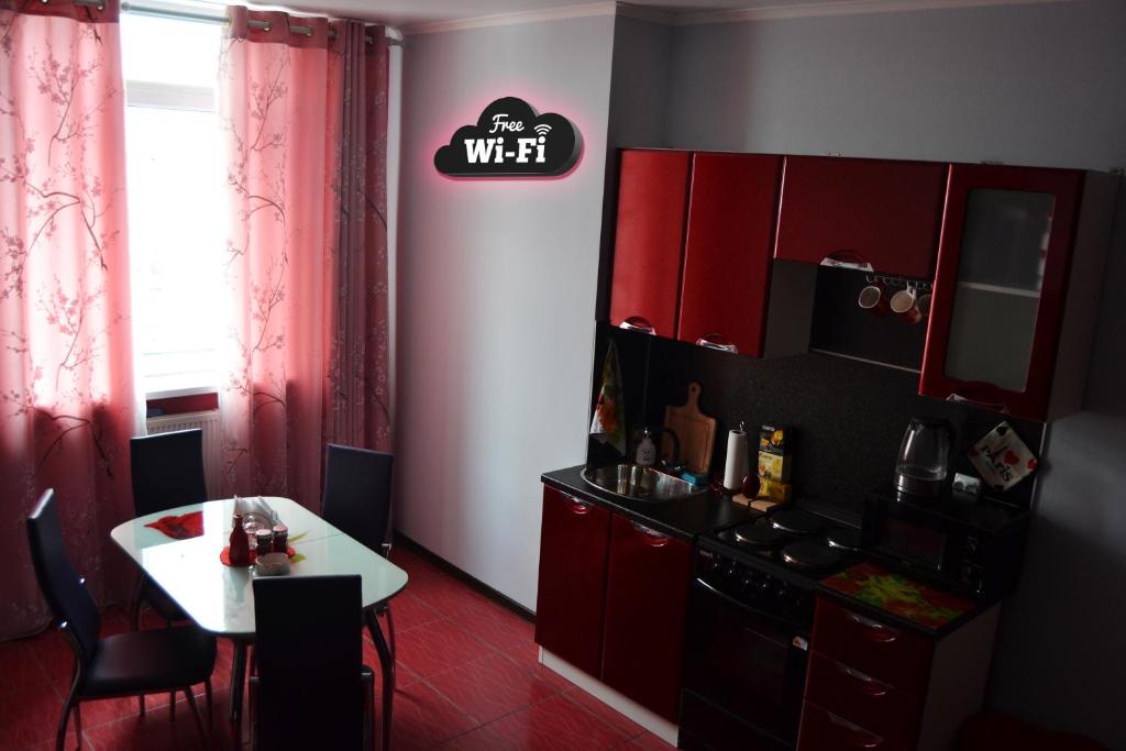 kuchnia z czerwonymi szafkami oraz białym stołem i stołem w obiekcie Apartments on Duki w mieście Briańsk