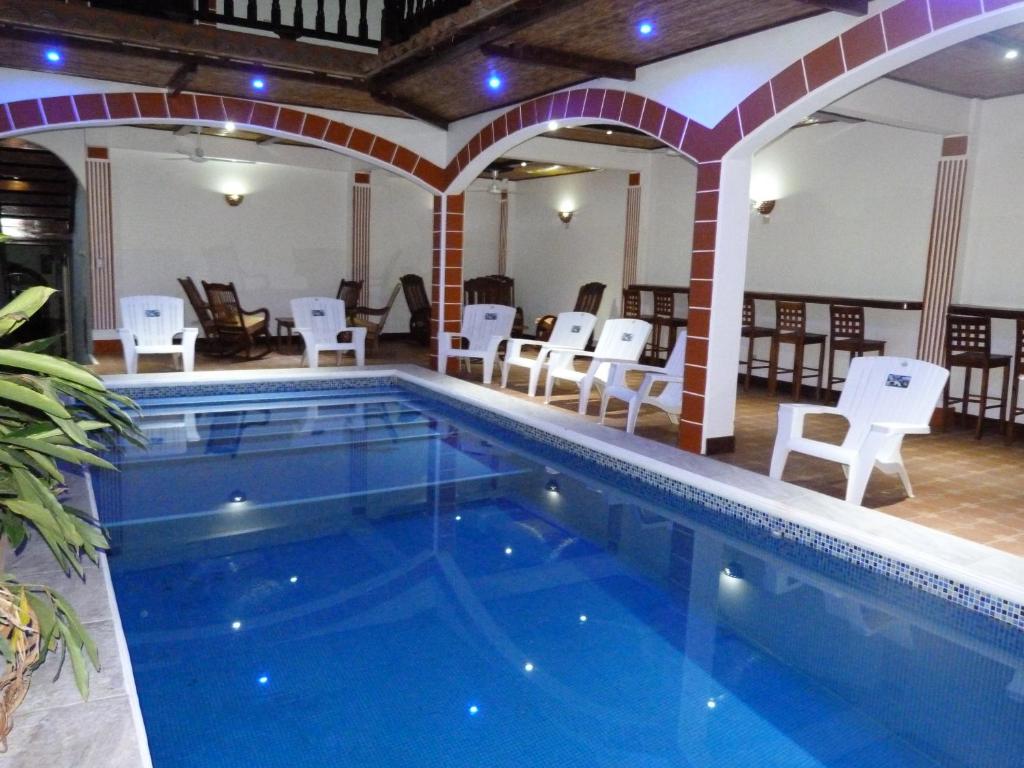 einen Pool in einem Hotel mit weißen Stühlen und Tischen in der Unterkunft Hotel La Gran Sultana in Granada