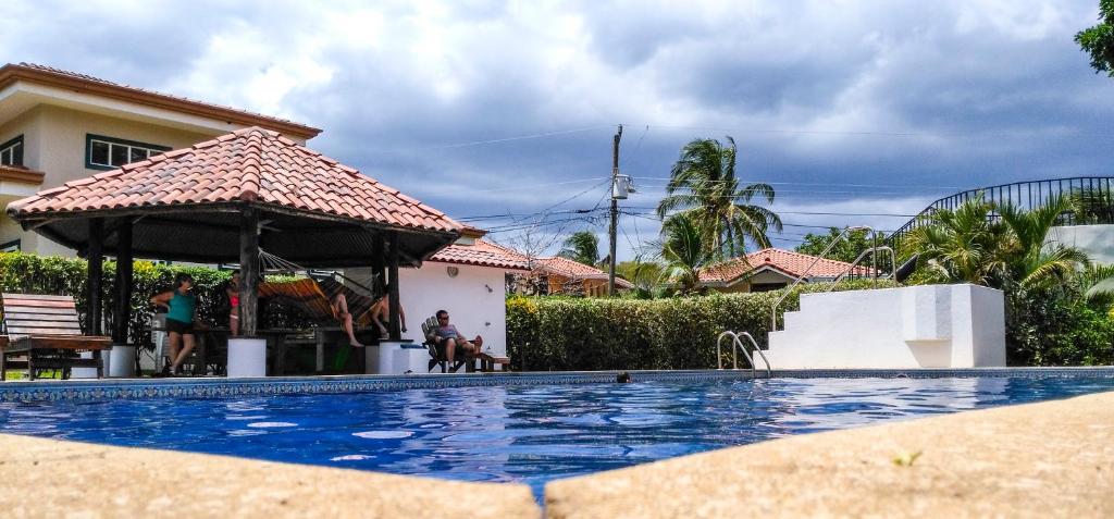 a swimming pool with a gazebo next to a house at Apartment in Hermosa's gardens in Playa Hermosa